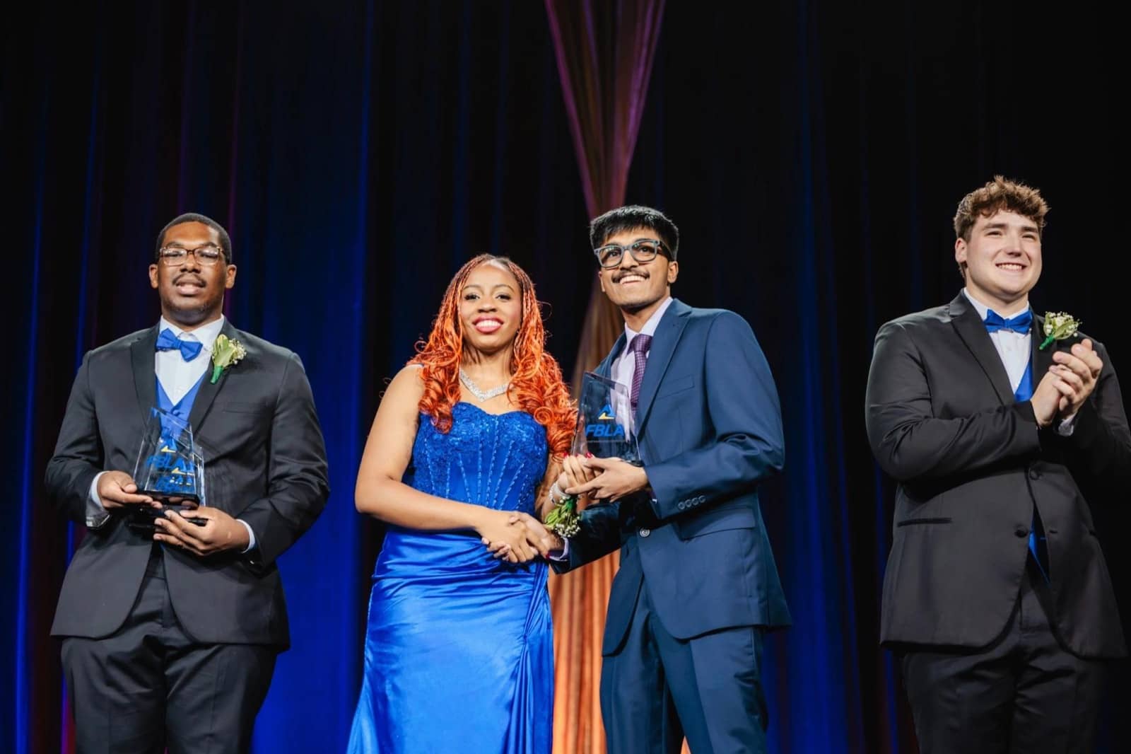 Sai Amartya on stage at the 2026 FBLA National Leadership Conference, shaking hands and holding the Organizational Leadership glass award.
